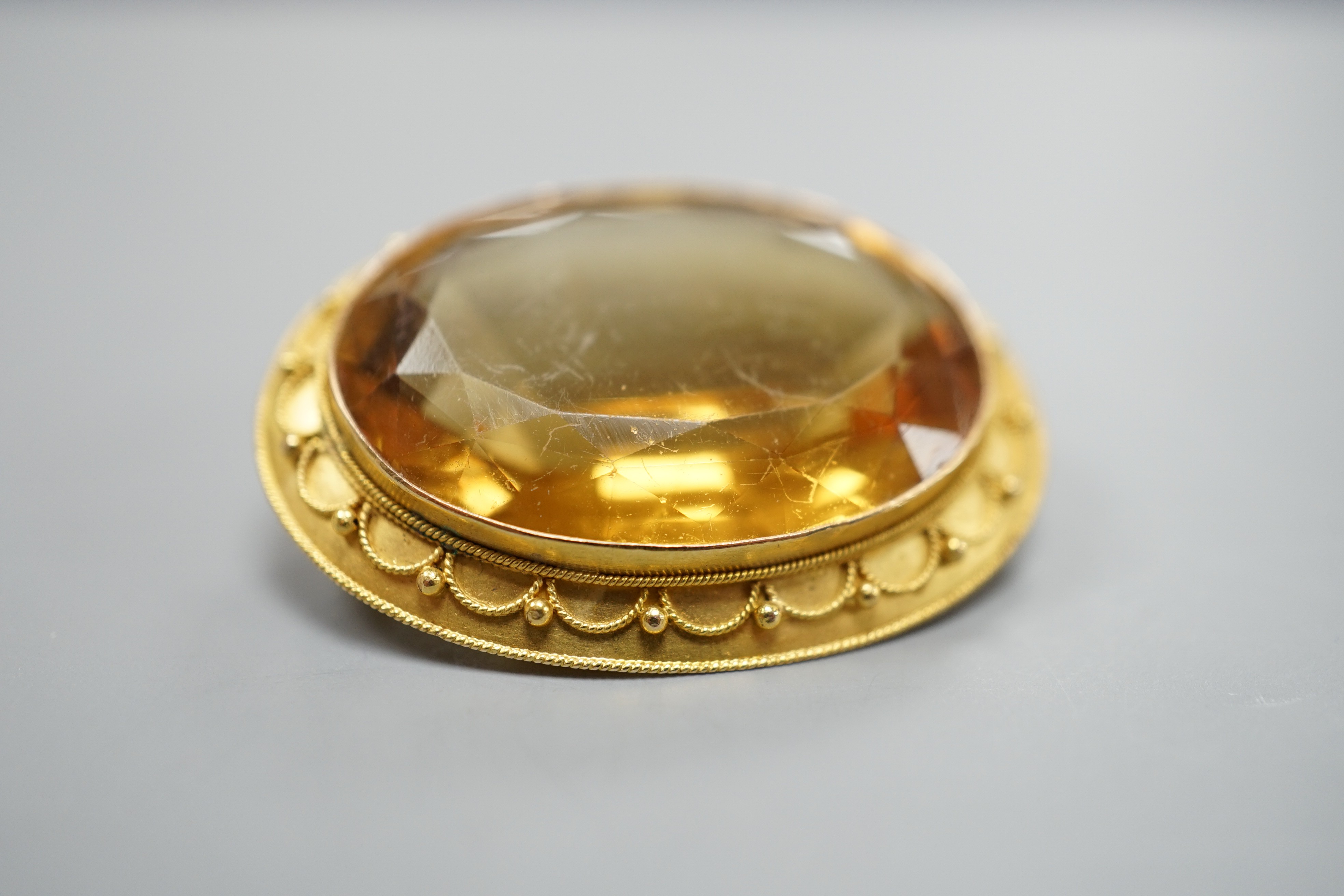A Victorian yellow metal and citrine set oval brooch, with cannetille work border, 35mm, gross weight 11.3 grams.